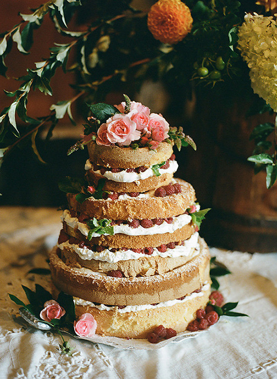 A beautiful tiered cake decorated with fresh raspberries and roses