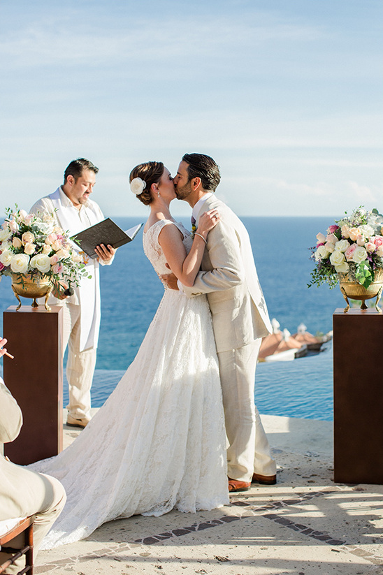 Newly married couple kissing at a scenic ocean view wedding ceremony