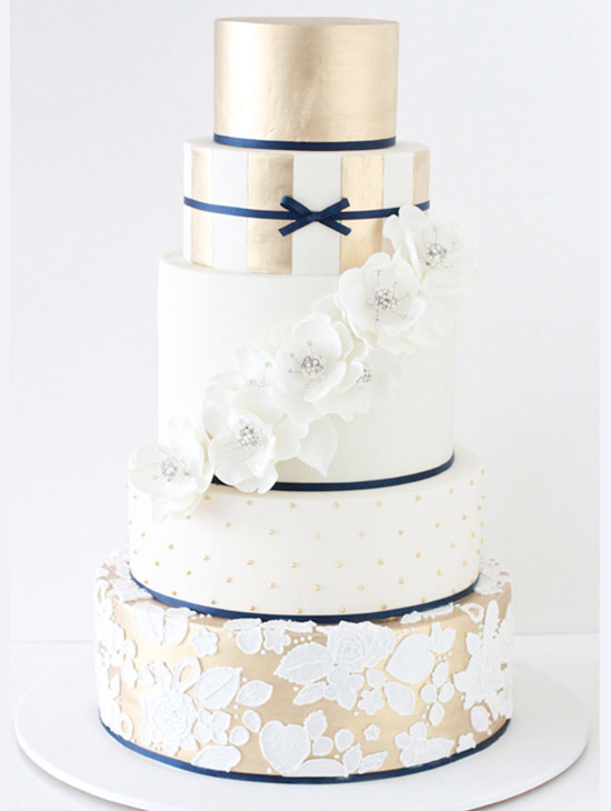 Elegant five-tier wedding cake with gold, white, and floral accents