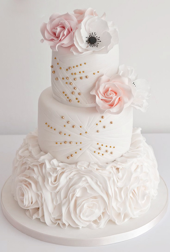 Elegant three-tier wedding cake with floral decorations and gold accents