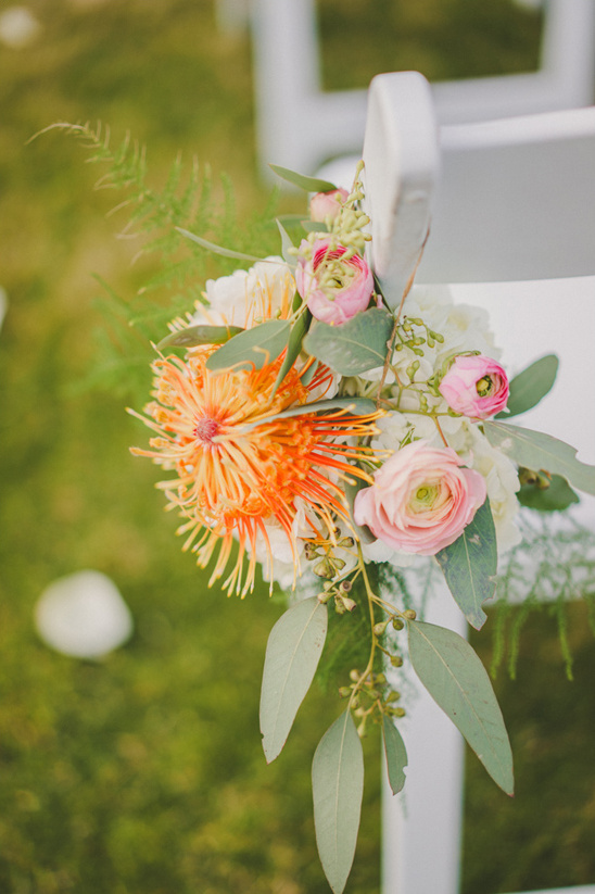 Wedding chair adorned with vibrant floral arrangement and greenery