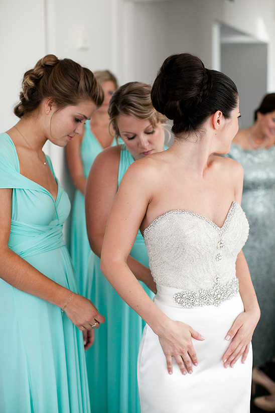 Bride getting ready in wedding dress with bridesmaids