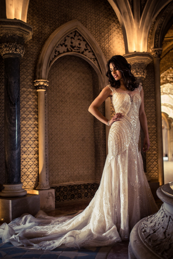 Elegant bride in a sparkling wedding gown in a historic archway