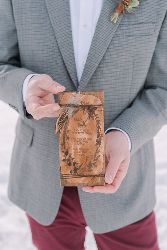 Groom holding wedding vows in a rustic wooden case, detail shot