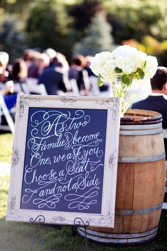 Wedding sign with message near a barrel and flowers