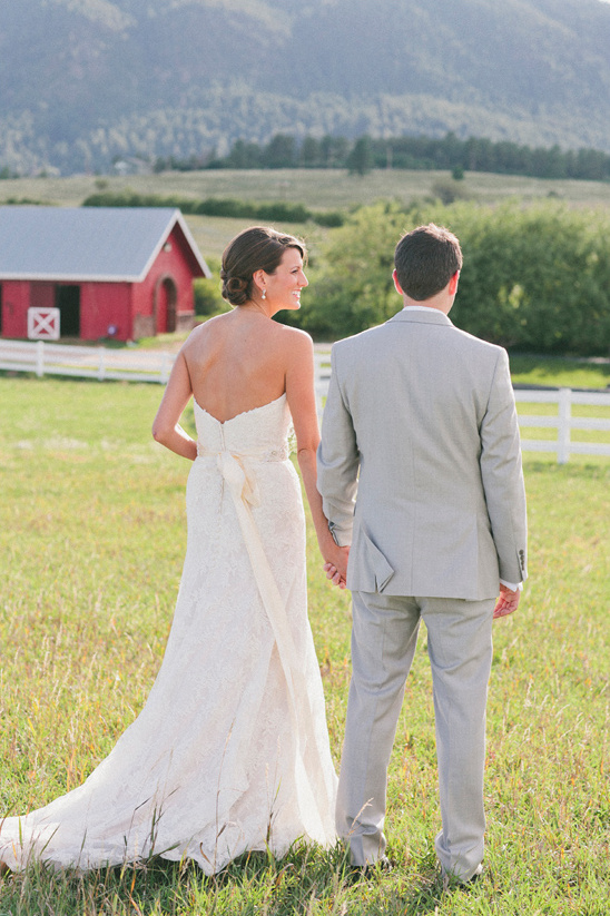 Bride and groom hold hands on their wedding day in a field