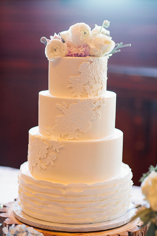 Elegant white wedding cake with floral decoration and lace design