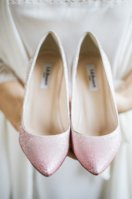 Sparkly pink bridal shoes held by a bride before the wedding