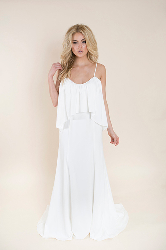 Elegant blonde woman in a white flowing wedding dress, looking at camera