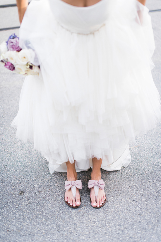 Bride wearing bow sandals with a white wedding dress and flowers
