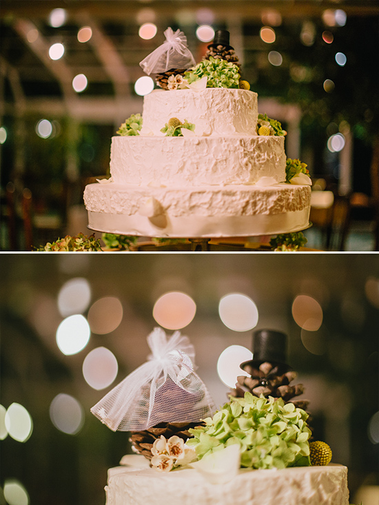 Elegant three-tiered wedding cake with decorative pine cone toppers