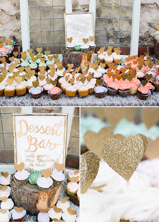 A beautifully decorated dessert bar with cupcakes and gold heart toppers