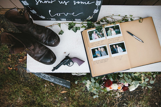 Wedding guestbook with photos and boots beside a toy gun