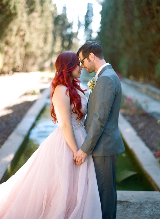 Loving couple on wedding day, red hair, pink dress, holding hands