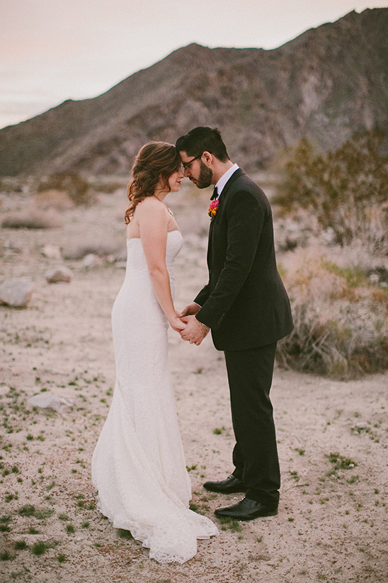 Bride and groom touching foreheads in desert wedding