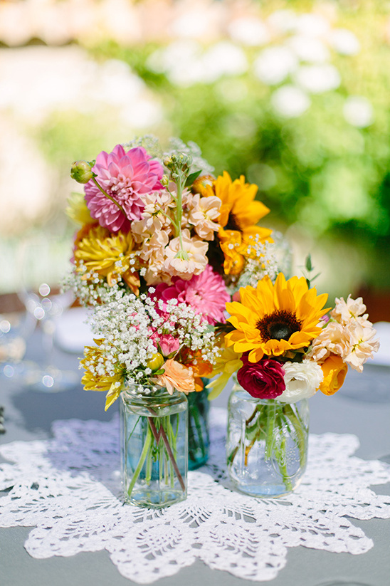 Colorful floral bouquets in mason jars on a lace doily for decoration