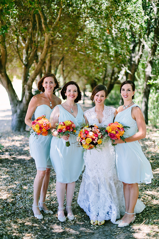 Bride and bridesmaids with bright bouquets pose for a photo