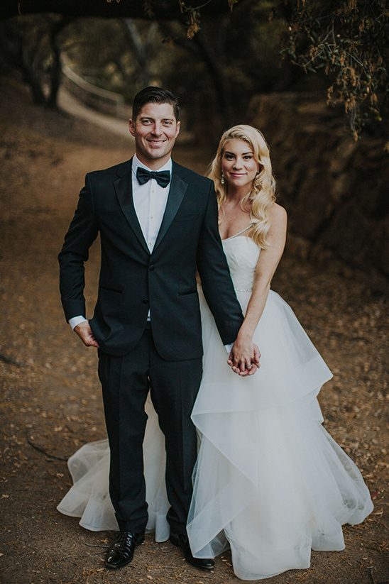 Happy couple dressed for their outdoor wedding, holding hands and smiling