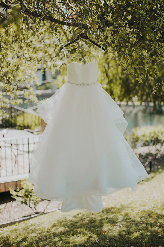 Elegant white wedding dress hanging from a tree branch