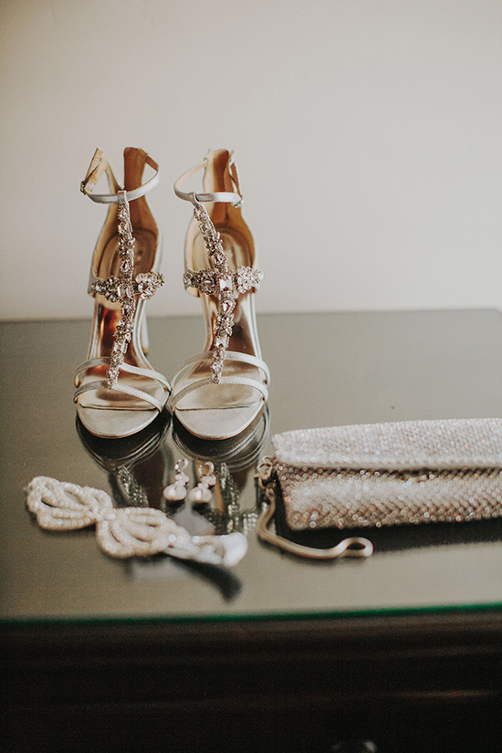 Elegant bridal shoes with accessories on a mirrored surface