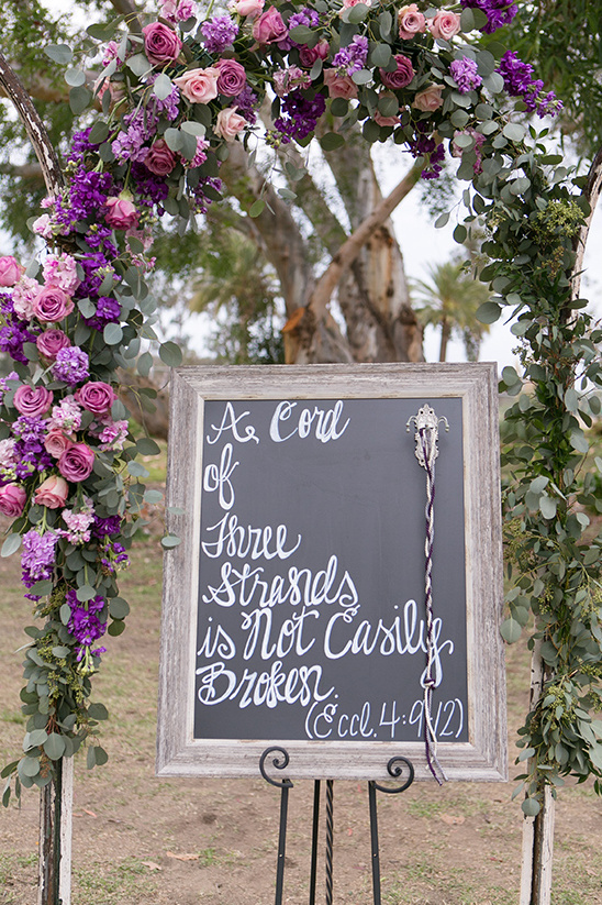 Wedding arch with floral decorations and a chalkboard quote