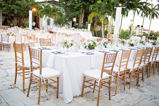 Elegant outdoor wedding reception setup with white tables and chairs