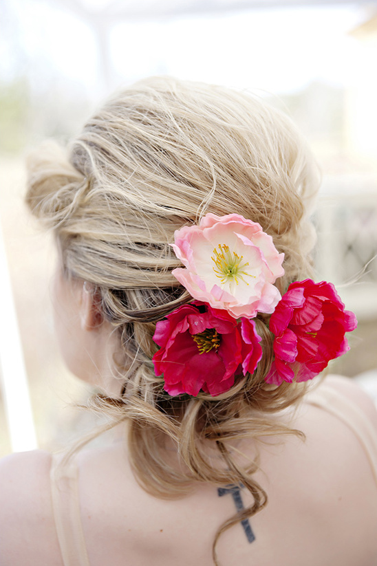 Blonde updo with vibrant pink and peach flower accents