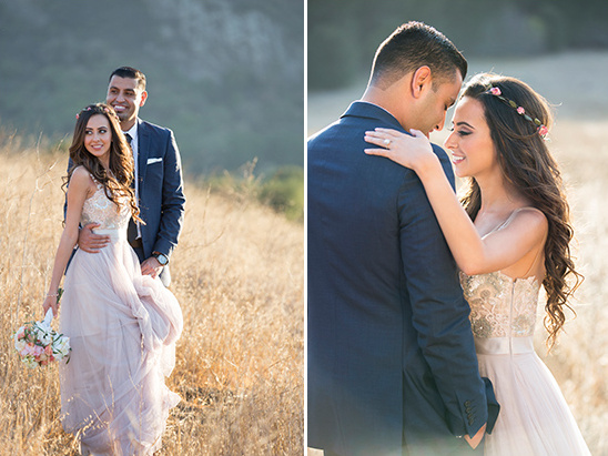 Smiling bride and groom embrace in a field during their wedding day