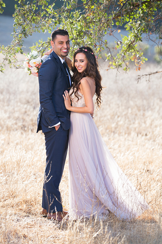Happy couple posing for wedding photo in a golden field