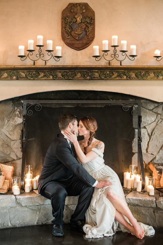 Romantic wedding couple kissing by candlelight fireplace