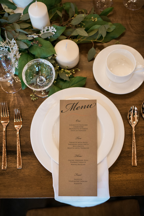 Elegant table setting with menu candles and greenery