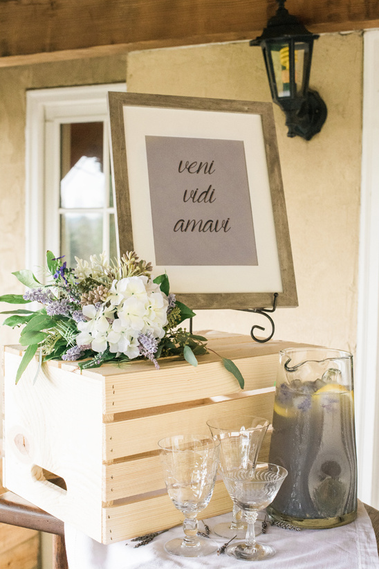 Wedding drink station with a latin phrase sign and flowers