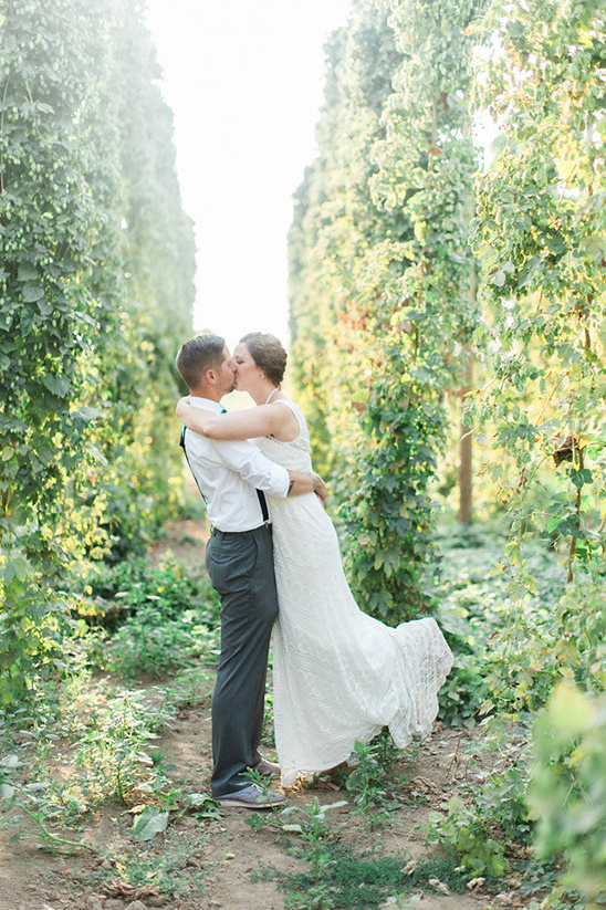 Newlyweds share a kiss amidst lush greenery, celebrating their wedding day
