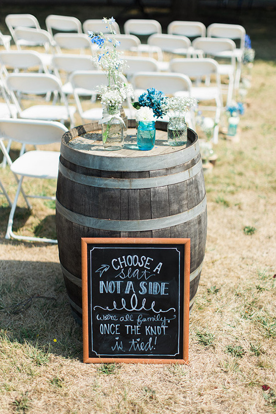 Wedding sign with flowers on barrel, invites guests to choose seats