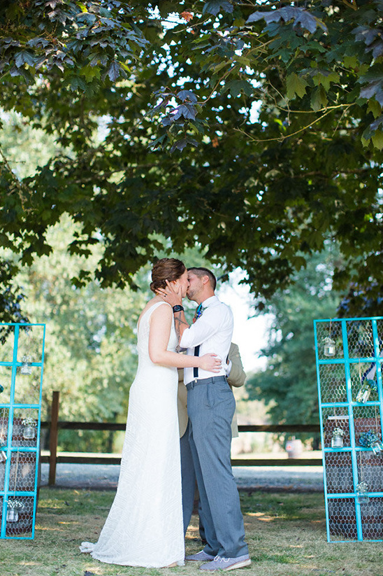 Couple shares a kiss during outdoor wedding ceremony under a tree