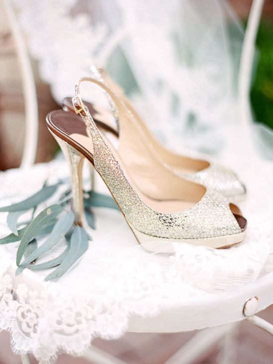 Sparkling bridal heels on a white lace chair, wedding detail