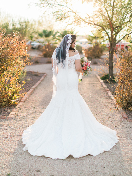 Elegant bride in a white wedding dress with veil, holding flowers