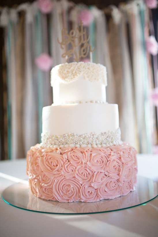 Elegant three-tiered wedding cake with rose frosting and decor