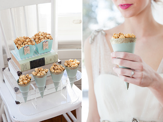 Caramel popcorn wedding treats in cones and boxes on a white chair