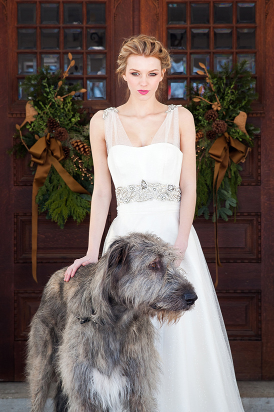 Bride in white wedding dress poses with a large dog for a photoshoot