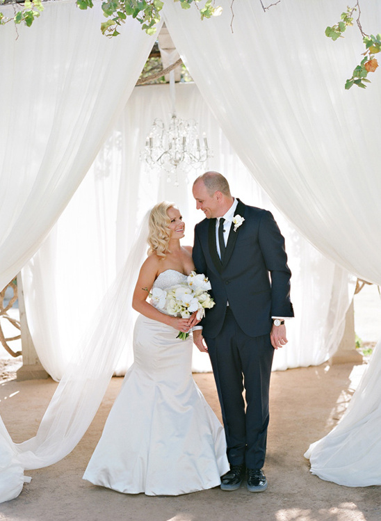 Happy couple at outdoor wedding ceremony with drapery