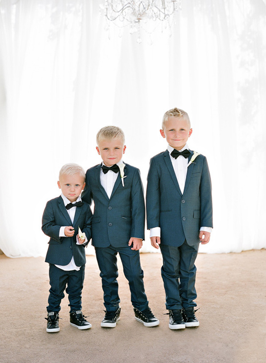 Three young boys wearing suits and bow ties with sneakers