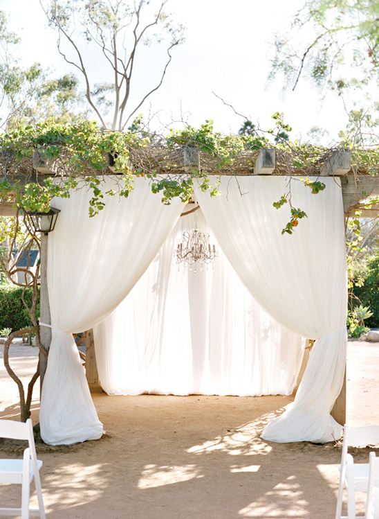 Elegant outdoor wedding ceremony arch draped with white fabric