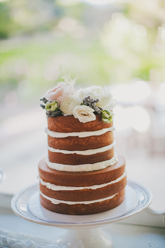 Naked wedding cake with white frosting and floral decoration on display