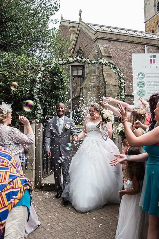 Happy couple exits church after wedding ceremony with confetti