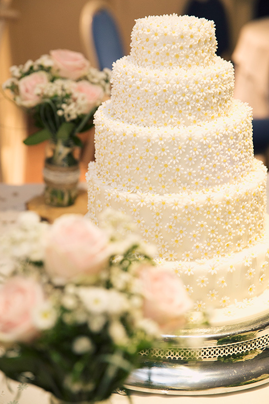 A beautifully decorated wedding cake with daisy flowers