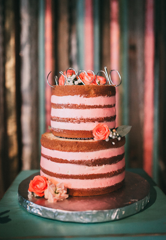 Rustic naked wedding cake with rose decorations and a cake topper