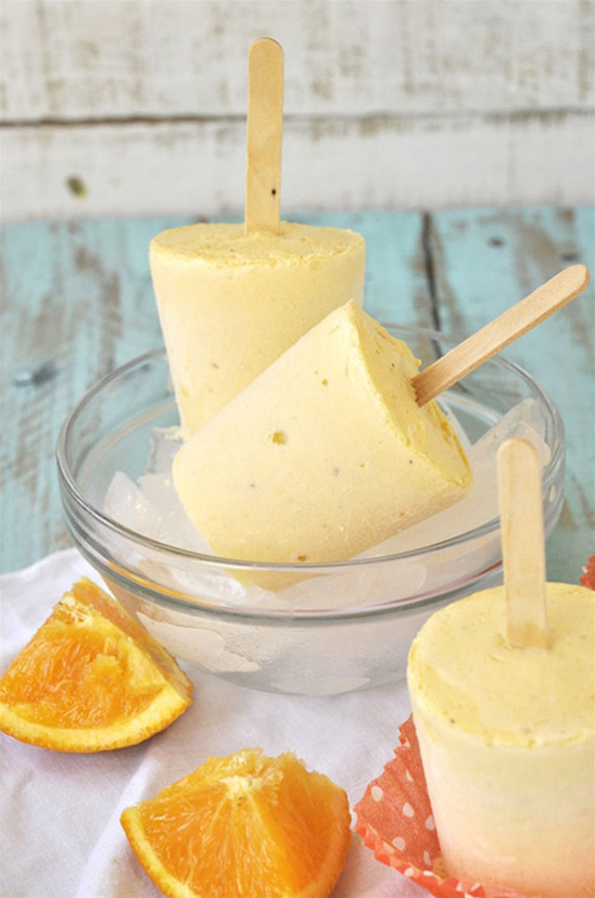 Orange popsicles with fresh fruit slices on ice