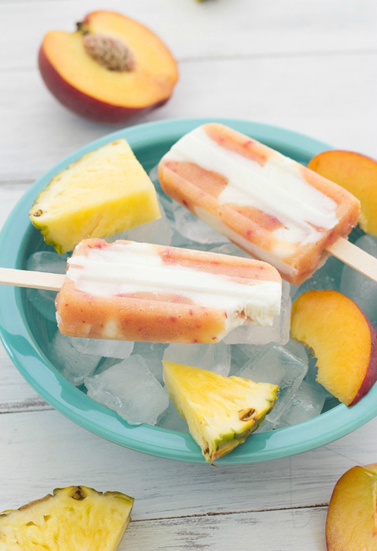 Refreshing peach pineapple popsicles on ice in bowl