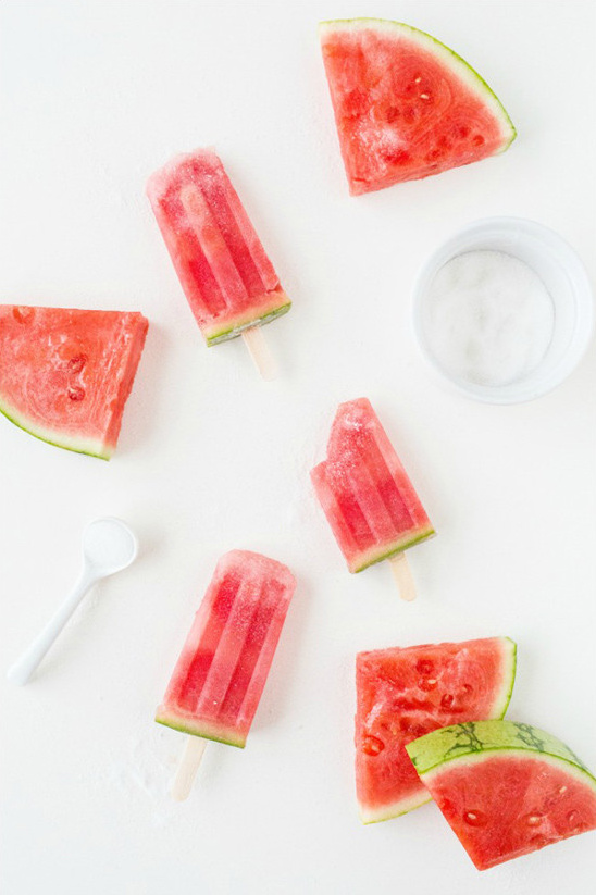 Refreshing watermelon slices and popsicles on white surface